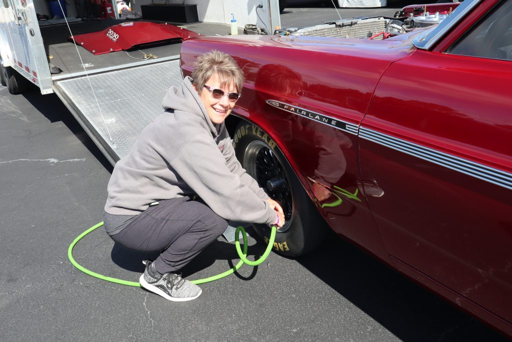 woman filling up tire on a 1967 Ford Fairlane drag car