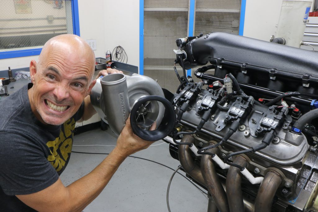man holding turbo near an ls engine