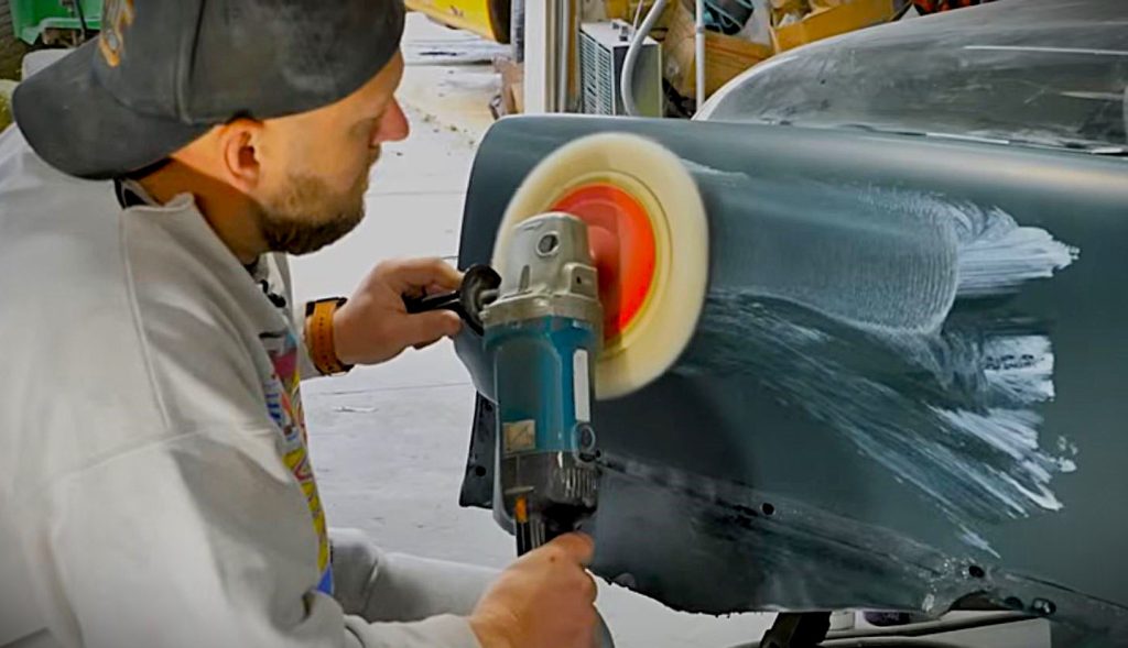 man using a buffer on a car fender