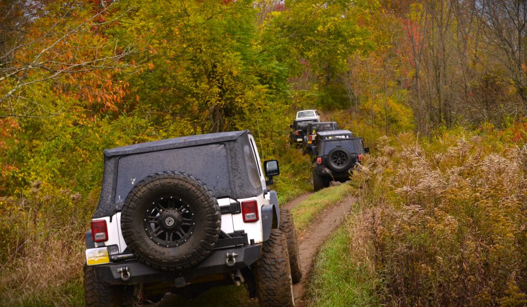 caravan of jeeps moving down trail in autumn