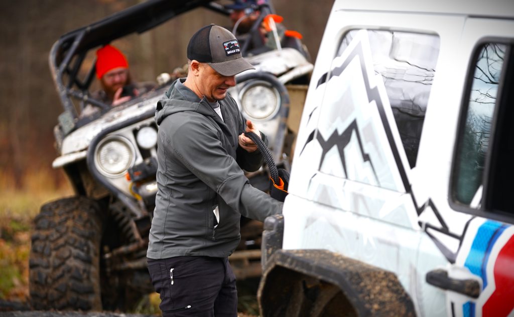 man removing recovery strap from jeep bumper
