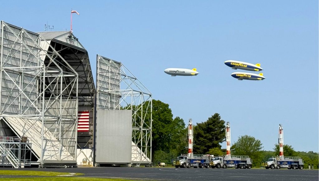 3 goodyear blimps aloft over airship hangar