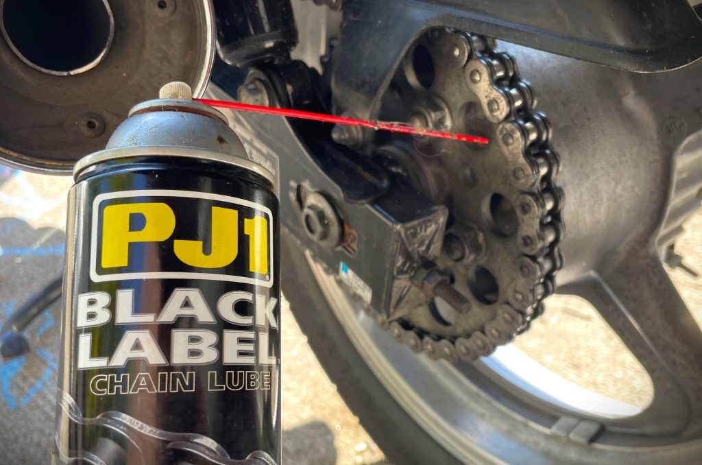can of motorcycle chain lube next to rear sprocket
