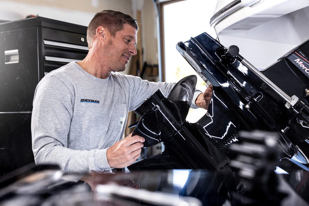 man servicing an outboard boat motor