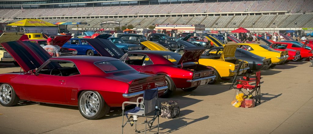 row of classic pony cars at a large show