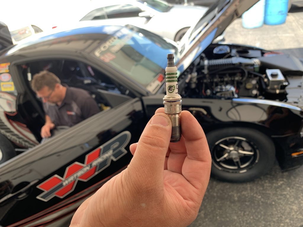 man holding spark plug in race pits