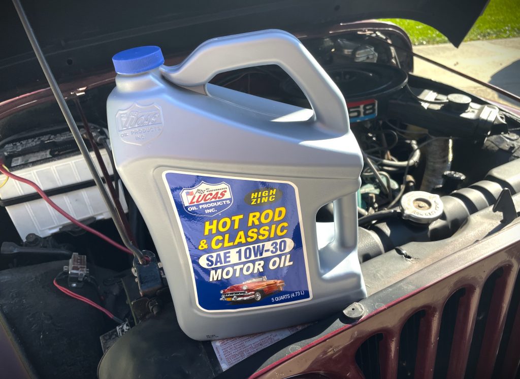 Jug of engine oil resting on grille of an old Jeep