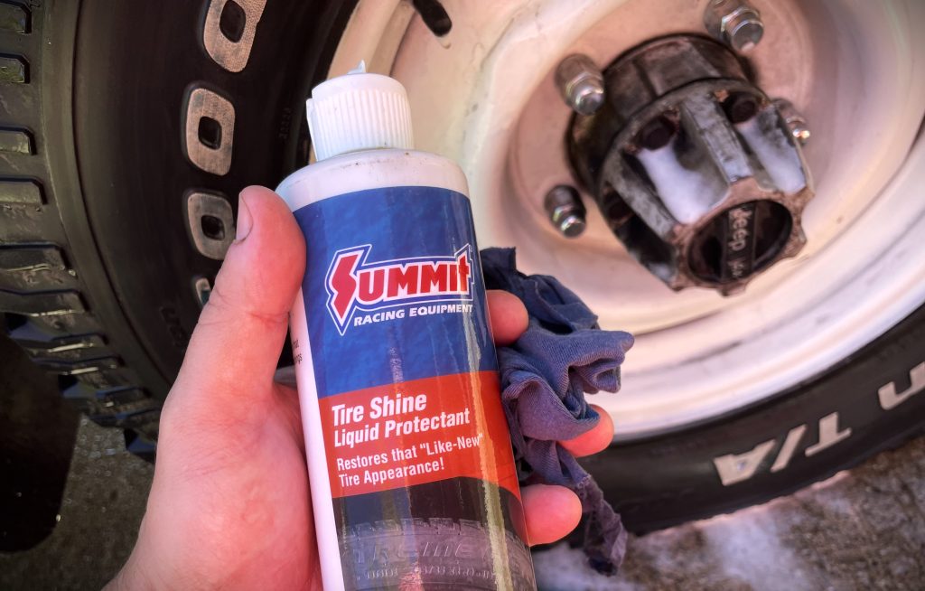 Man Holding Can of Tire Shine Near Wheel