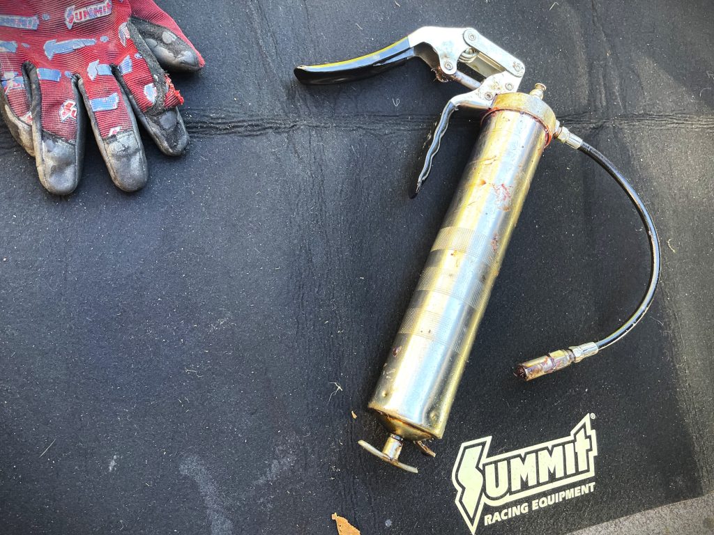 grease gun resting atop an oil change mat