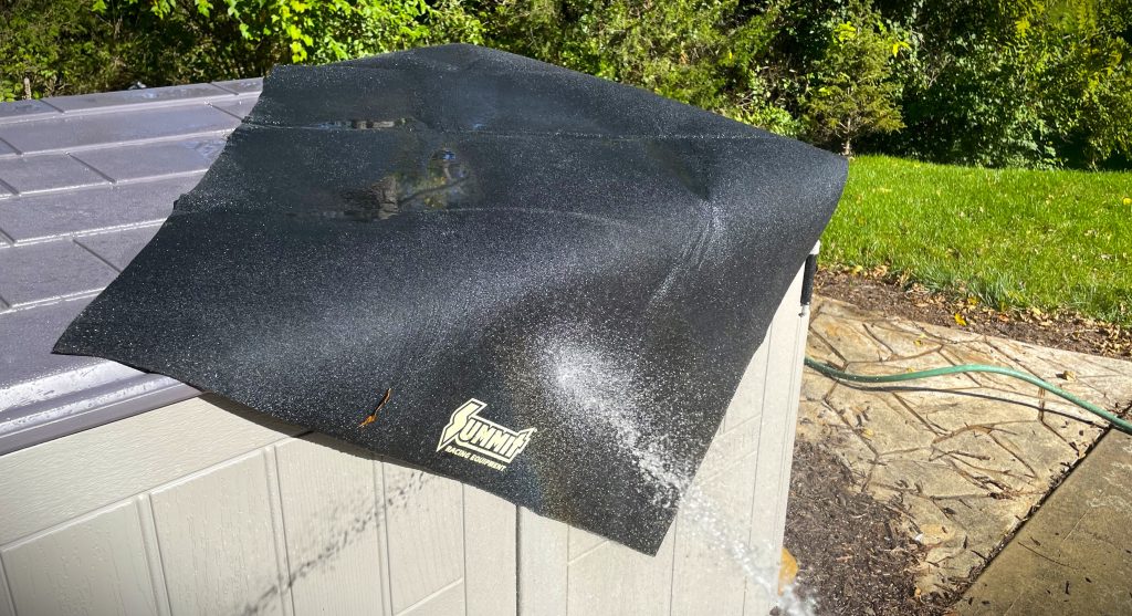 washing an oil change mat with hose