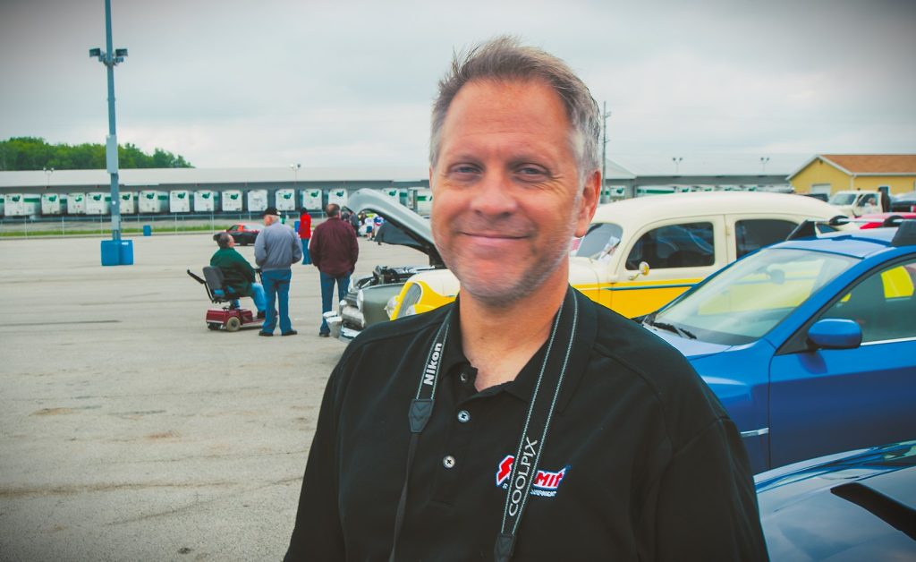 man posing for photo at a car show
