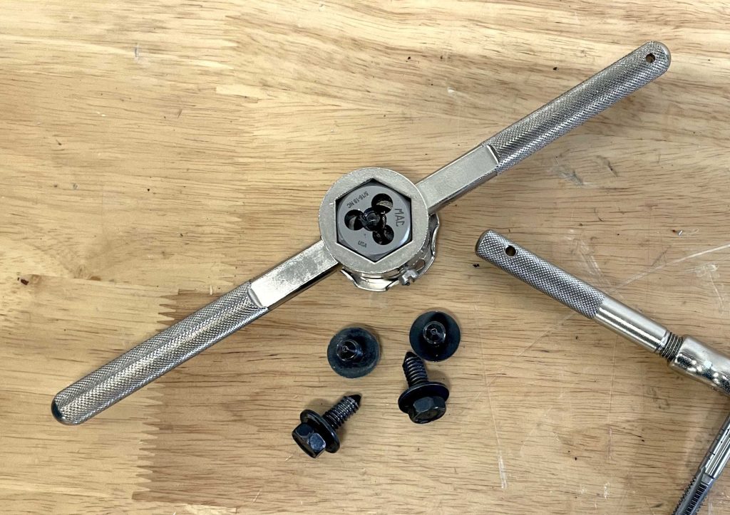 Cleaning shock mount screw threads with tap and die tool