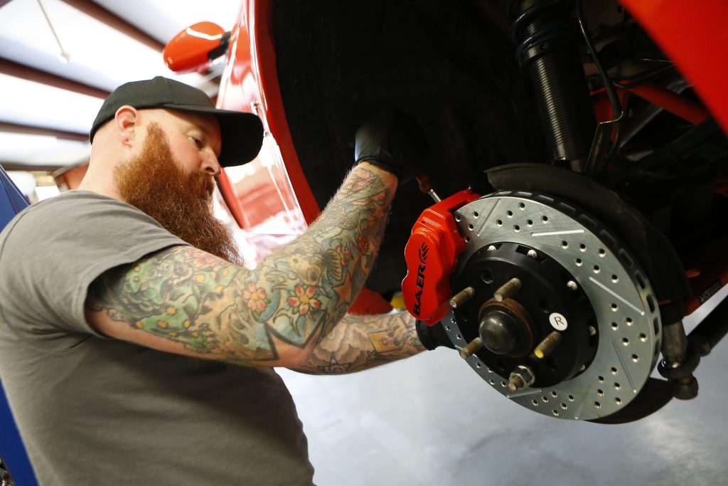 man installing a brake caliper on a car