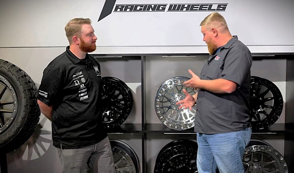 two men talking near a rack of custom wheels